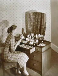 Kvinna vid hennes toalettbord, ca 1955 (sepiafoto)